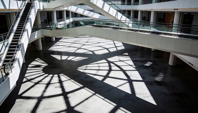 Sunlit atrium with geometric skylight shadows and modern escalators