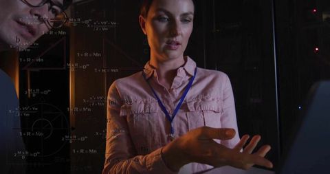 Female engineer presenting data visualization on transparent screen in dim server room