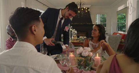 Groom serving wine at elegant indoor dinner celebration