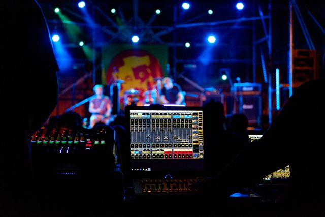 Sound engineers controlling the audio mixer during a live music event. Perfect for themes related to concerts, live performances, music events, and behind-the-scenes production work.