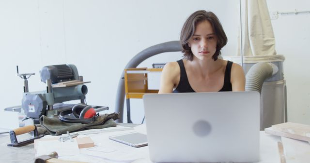 Focused Young Woman Working on Laptop in Workshop Environment - Download Free Stock Images Pikwizard.com