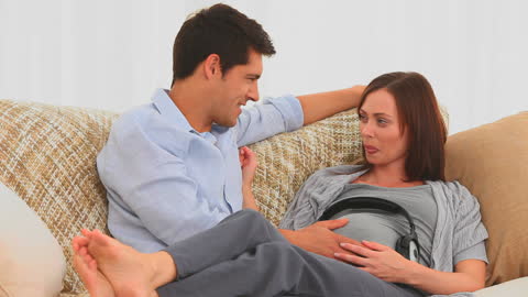 Expecting Couple Sharing Music with Future Baby on Couch