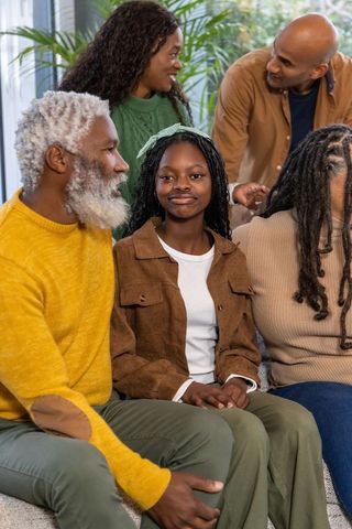Multi-generational family gathering on sofa with smiling teen girl and elders