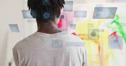 Man with dreadlocks using holographic interface in creative studio with colorful mural