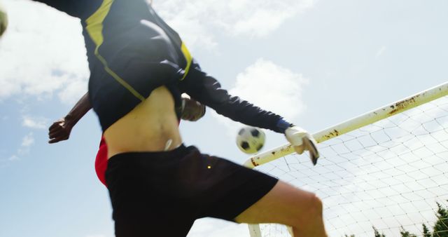Soccer players attempting to score a goal under a sunny sky. Great for use in sports advertisements, athletic promotions, team sports training materials, and articles focusing on fitness and teamwork.