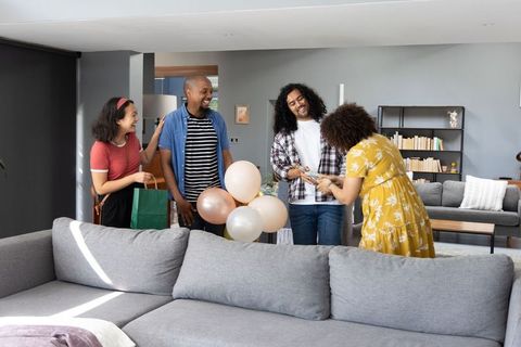 Diverse Friends Gathering with Gift and Balloons in Cozy Living Room