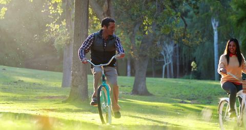 Happy Couple Cycling in Sunlit Park - Download Free Stock Images Pikwizard.com