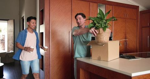Diverse Couple Unpacking New Home with Houseplant