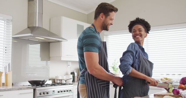 A couple is seen enjoying quality time preparing vegetables together in a modern kitchen. Perfect to depict themes of love, partnership, domestic chores, healthy living, and joyful cooking experiences. Ideal for advertisements, lifestyle blogs, cooking websites, and social media posts focused on relationships and home life.
