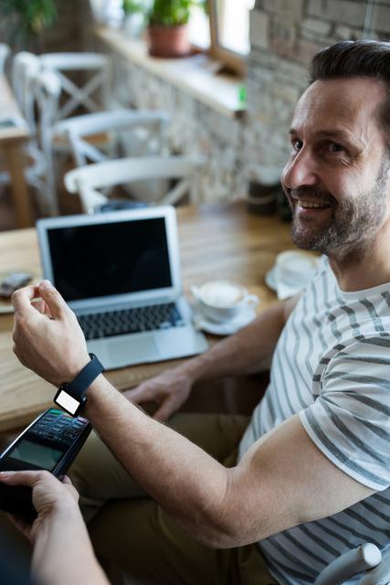 Man using smart watch for express pay in coffee shop