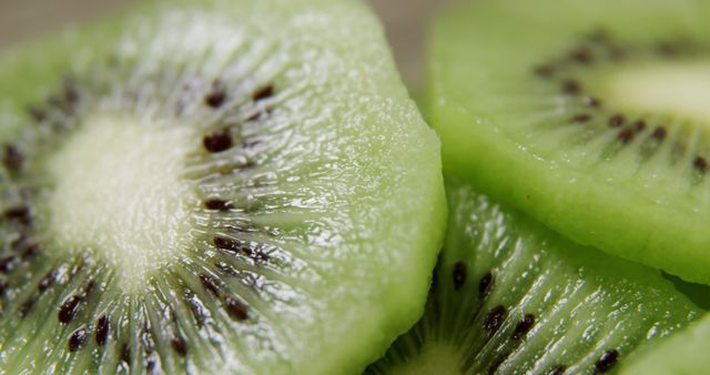 Close-up view of fresh kiwi slices showing juicy texture and vibrant green color. Great for illustrating healthy eating, nutrition, fresh produce, and recipes. Useful for food blogs, nutrition articles, and health-related promotions.