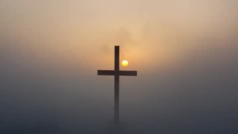 Sunrise Behind Cross Creating Silhouette in Misty Morning
