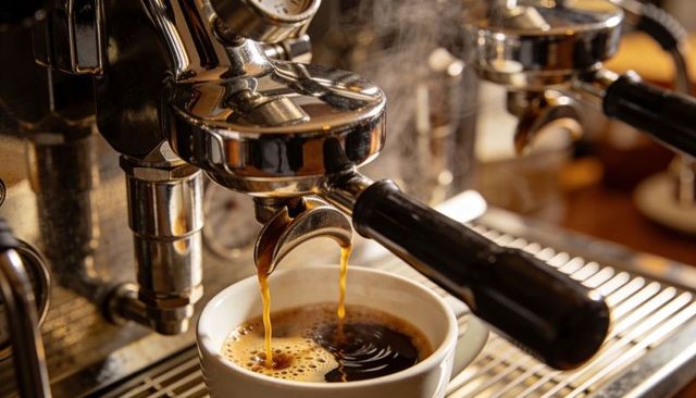Extracting espresso from commercial machine producing thick crema with steaming reflections
