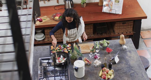 Woman with curly hair cooking vegetable stir-fry in modern kitchen - Download Free Stock Images Pikwizard.com