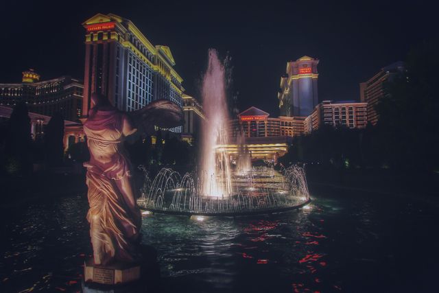 This captivating night scene in Las Vegas showcases a beautifully illuminated fountain and statue, set against the backdrop of the iconic Caesars Palace. Perfect for use in travel brochures, tourism websites, or advertisements for luxury accommodations. The dramatic lighting and reflections in the water add an element of elegance and allure to this vibrant cityscape.