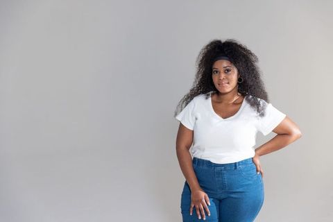 African american woman posing in white v-neck and denim with headband and gold hoops