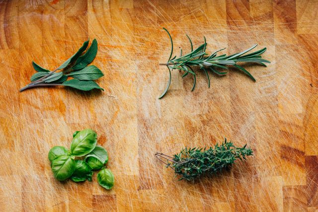 This image shows a variety of fresh herbs arranged on a wooden cutting board. It includes basil, rosemary, thyme, and sage, perfect for use in culinary and cooking projects, health and wellness blogs, or organic food articles. Ideal for any content related to healthy eating, food preparation, or kitchen aesthetics.