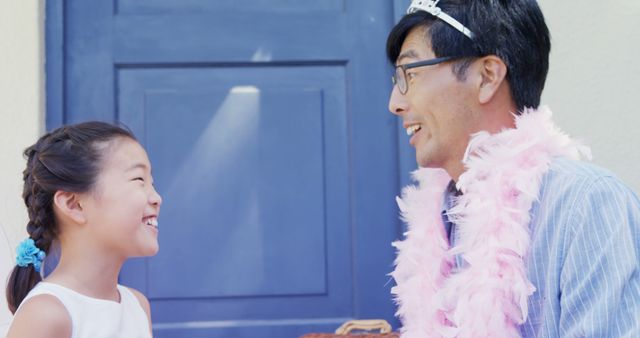 Father and daughter enjoying quality time together. Father wearing feather boa and playful accessories, engaging in dress-up game. Ideal for themes of family bonding, love, parental relationships, humor, and joy. Great for use in family-oriented advertisements, parenting blogs, and lifestyle articles.