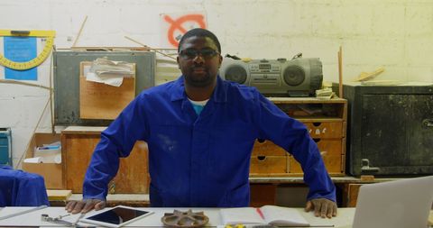 Foundry worker in blue uniform posing in workshop with gadgets