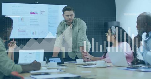 Business leader presenting analytics to diverse team in conference room with data overlays