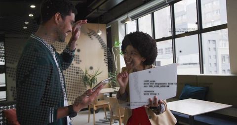 Young professionals collaborating over printed code and tablet in modern coworking space