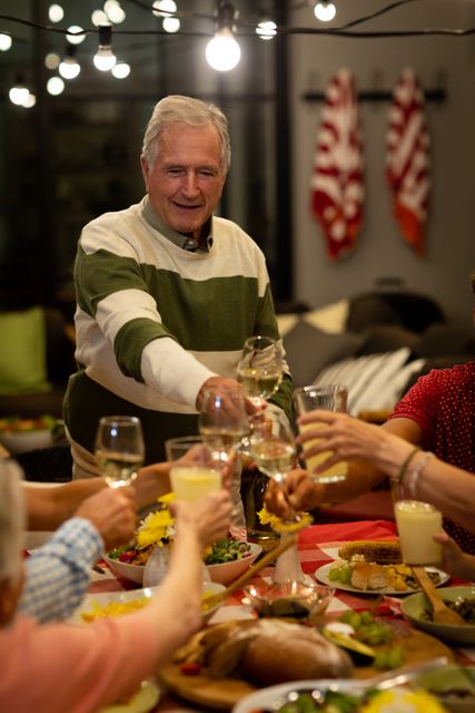 Multi-generation Caucasian family enjoying a meal together at home, raising glasses in a toast. Perfect for themes of family bonding, celebrations, festive gatherings, and home life. Ideal for use in advertisements, family-oriented content, and lifestyle blogs.