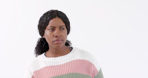 Woman in Cozy Striped Sweater Looking Pensive Against White Background