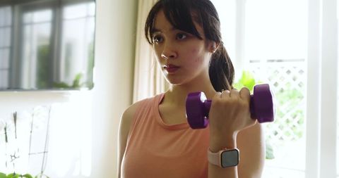 Asian Woman Exercising at Home with Dumbbell and Smartwatch