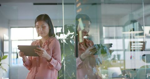 Office professional using tablet with reflection in glass