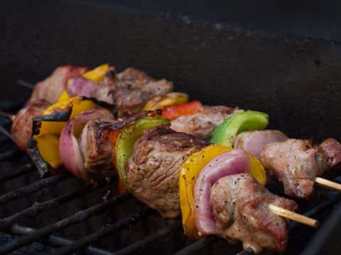 Juicy grilled meat skewers with bell peppers and red onion on charcoal grill