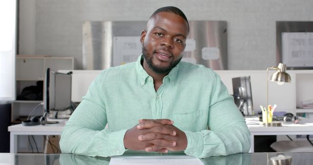 Confident businessman giving a presentation sitting at a desk in a modern office environment. Perfect for business training materials, corporate communications, and professional presentation concepts.