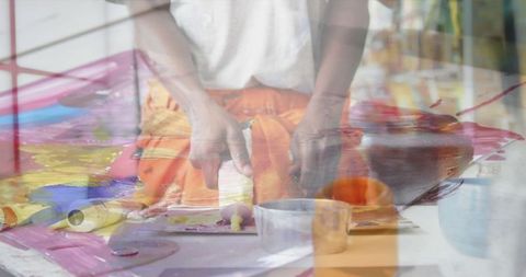 Creative hands painting with vibrant colors blending digital overlay