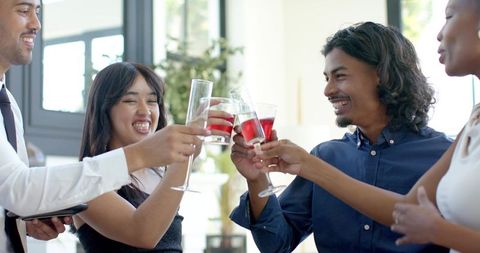 Young professionals toasting red wine in modern office lounge during celebration