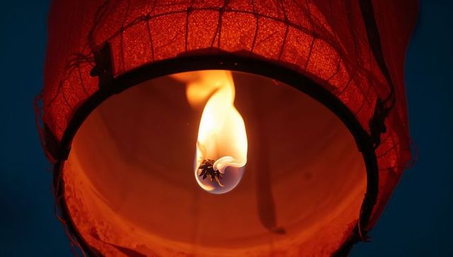 Floating red lantern with flickering candle flame at night