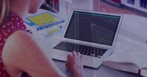 Young Woman Coding on Laptop in Library Workspace with Books and Notebook