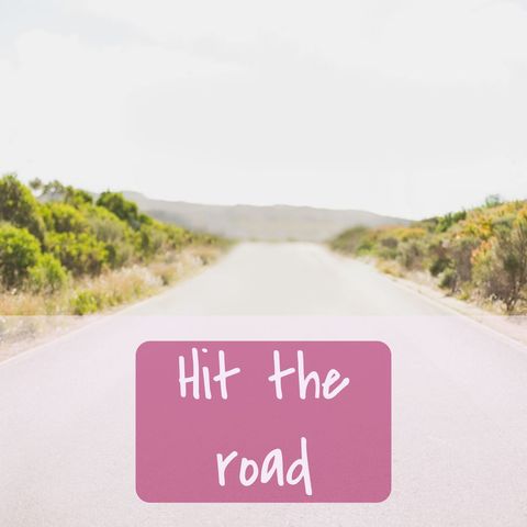 image features an open road extending towards the horizon under clear sky with vibrant greenery on either side. foreground includes an overlay text 'hit the road', encouraging travel or adventure. ideal for use in travel blogs, motivational social media posts, or lifestyle magazines focusing on outdoor exploration and adventures.