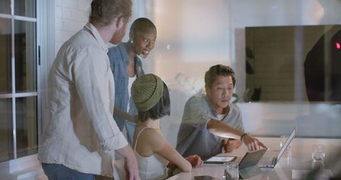 Diverse team collaborating with technology in modern office at night