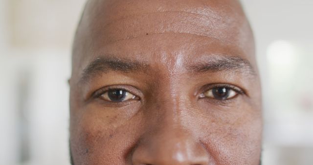 Close-up shot of a mature African American man's face, highlighting intense facial expressions. Detail of the skin is visible, including wrinkles and texture, emphasizing experience and wisdom. Shows a serious, concentrated look suitable for themes like determination, focus, aging, and identity. Ideal for use in advertisements, editorial content, or personal development campaigns.