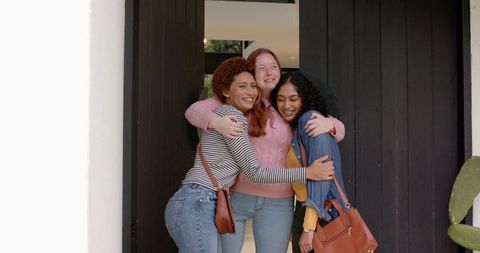 Diverse female friends embracing warmly at modern front door