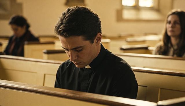 Young priest bowing head in church pew reflecting in quiet moment of prayer and solitude