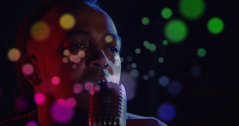Soulful singer performing on dimly lit stage with vintage microphone