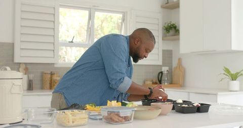African american man meal prepping healthy lunches on bright modern kitchen island