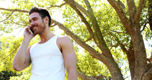 Smiling Man Talking on Phone Outdoors in Sunny Park - Download Free Stock Images Pikwizard.com