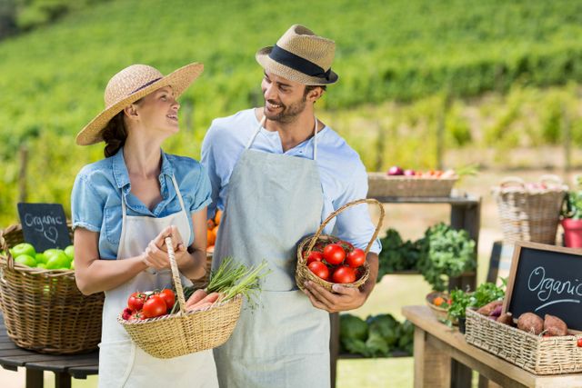 Happy couple holding fresh vegetables in baskets at farm