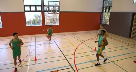 Male Basketball Team Training on Gymnasium Court with Drills