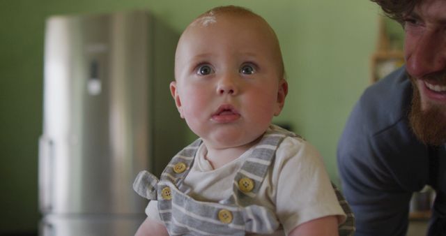 Portrait of happy caucasian baby looking at camera in kitchen. homesteading, healthy lifestyle on organic farm in the countryside.