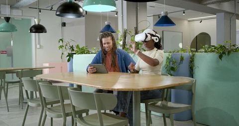 African american coworkers testing vr headset collaborating via tablet in modern coworking lounge