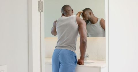 Man Checking Hairline in Bathroom Mirror for Grooming Routine