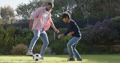Father and Son Practicing Soccer on Green Backyard Lawn