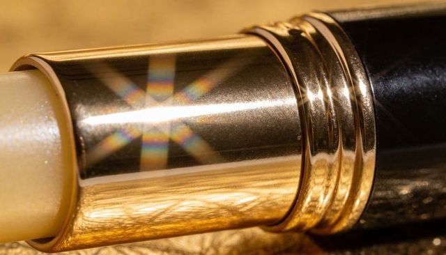 Gold lipstick tube with pearlescent balm, polished rings and mirrored metallic finish